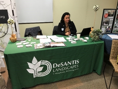 A person sits at a green table displaying brochures and business cards.